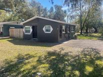 Dark brown house with white trim, front yard, and wooden fence at 1009 W Washington St, Plant City, FL 33563