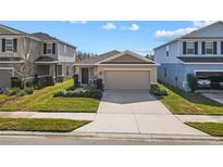 Tan one-story house with a two-car garage and a well-maintained lawn at 10773 Hawks Landing Dr, Land O Lakes, FL 34638