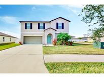 Charming two-story home featuring a well-manicured lawn, attached garage, and covered front porch at 3059 Nubbin Ridge Ln, Zephyrhills, FL 33540