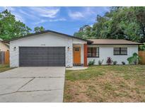 Updated home exterior with modern gray garage door and orange front door at 3445 10Th N Ave, St Petersburg, FL 33713