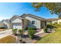 Beige house with double garage and landscaped front yard at 5909 Yorkshire Dr, Zephyrhills, FL 33542