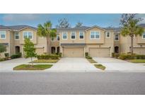 Tan three-story townhome with two-car garage and lush landscaping at 10108 Newel Valley Loop, Riverview, FL 33569
