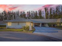 Tan house with gray roof, carport, and landscaping at dusk at 1752 Atrium Dr, Sun City Center, FL 33573