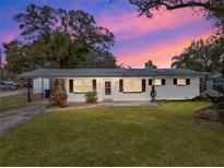 Ranch style home with white exterior, landscaping, and a spacious lawn at 8002 Sane Pl, Tampa, FL 33610