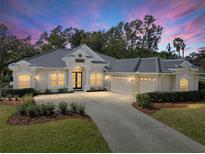 Beautiful one-story home with a three-car garage, lush landscaping, and a circular driveway at 12632 Oak Hollow Ct, Dade City, FL 33525