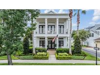 Stunning two-story home featuring a columned porch, balcony, an American flag, and beautiful landscaping at 10444 Green Links Dr, Tampa, FL 33626