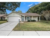 Brick ranch home with attached garage, and a well-manicured lawn at 10504 Tapestry Dr, Port Richey, FL 34668