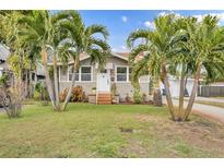 Charming bungalow with a white door, palm trees, and well-manicured lawn at 1161 35Th N Ave, St Petersburg, FL 33704