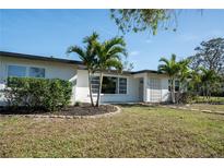 White, single story home with palm trees and landscaped yard at 1309 Nokomis S Ave, Venice, FL 34285