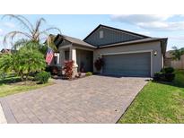 Single-story home with gray siding, paver driveway, and landscaping at 15720 Buckford Landing Pl, Sun City Center, FL 33573