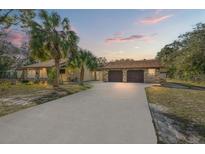 House exterior featuring a two-car garage and a spacious driveway at 18801 Orange Hill Dr, Hudson, FL 34667
