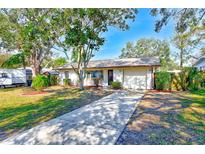Cute ranch home with a paved driveway, mature landscaping, and a detached garage at 21 Belle Meade Cir, Largo, FL 33770