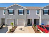 Gray townhome with two-car garage and landscaped front yard at 32241 Turtle Grace Loop, Wesley Chapel, FL 33545