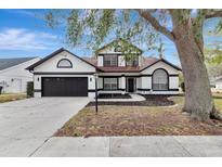 Two-story house with a dark brown and white exterior, landscaping, and a driveway at 3404 Shady Brook Ln, Sarasota, FL 34243