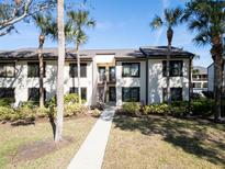Condo building exterior with walkway, landscaping, and palm trees at 355 Moorings Cove Dr # 355, Tarpon Springs, FL 34689