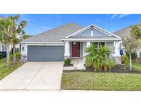 One-story home with gray siding, red door, and landscaping at 5629 Maidenstone Way, Palmetto, FL 34221
