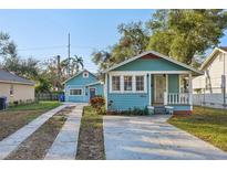 Charming blue bungalow featuring a quaint front porch and a long driveway to the garage at 612 12Th S Ave, St Petersburg, FL 33701