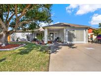 Single-story home with landscaped yard, driveway, and mature tree at 9445 Barnstead Ln, Port Richey, FL 34668