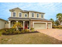 Two-story house with a red door, stone accents, and a three-car garage at 11550 Lake Lucaya Dr, Riverview, FL 33579