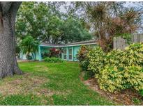 Light teal house with mature landscaping and a spacious yard at 13851 102Nd Ave, Largo, FL 33774