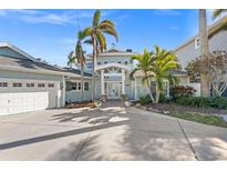 Stunning waterfront home with a light teal exterior, palm trees, and a two-car garage at 17077 Dolphin Dr, North Redington Beach, FL 33708