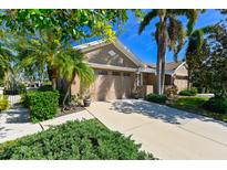 Tan house with two-car garage, lush landscaping, and a paved driveway at 7402 Hamilton Rd, Bradenton, FL 34209