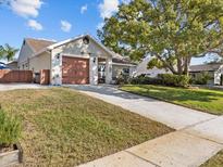 Charming single-story home features a well-maintained lawn and an attached two-car garage at 807 Cavemill Way, Tarpon Springs, FL 34689