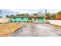 Charming light teal single story home with a circular driveway and white vinyl fence at 1130 Queen N St, St Petersburg, FL 33713