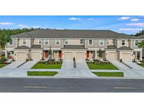 Front view of townhouses with attached garages and landscaping at 2071 Hallier Cv, Wesley Chapel, FL 33543