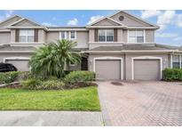 Two-story townhome with two-car garage and landscaped front yard at 26914 Juniper Bay Dr, Wesley Chapel, FL 33544