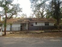 Modest single-story home featuring a garage, covered front entry, and chain-link fence at 3401 Riderwood Dr, Dade City, FL 33523