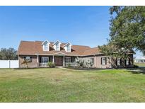 Brick home with a large front porch and a well-maintained lawn at 3717 Quail Nesting Pl, Plant City, FL 33565