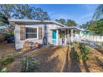 Charming bungalow with a teal door, landscaping, and a white picket fence at 6327 Emerson S Ave, St Petersburg, FL 33707