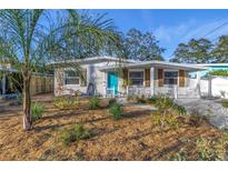 Charming bungalow with a teal door, white picket fence, and manicured landscaping at 6327 Emerson S Ave, St Petersburg, FL 33707