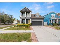 Two-story house with gray siding, yellow door, and landscaped front yard at 7602 S Desoto St, Tampa, FL 33616