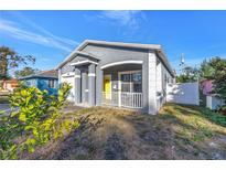 Newly renovated gray house with yellow door, white porch and a fenced yard at 1410 Prescott S St, St Petersburg, FL 33712