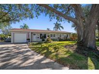 Charming ranch home with a spacious lawn, mature trees, and a paved driveway at 1690 74Th N Ave, St Petersburg, FL 33702