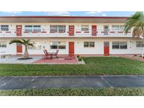 Red and white condo building with a well-maintained lawn and patio at 1950 58Th N Ave # 9, St Petersburg, FL 33714