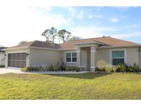 Tan one-story house with brown roof, attached garage, and landscaped lawn at 2098 Zellwood Ter, North Port, FL 34286