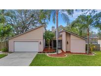 Tan house with white garage door, landscaping, and palm trees at 2826 Kavalier Dr, Palm Harbor, FL 34684