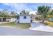 Front view of a white mobile home with carport at 37418 Hammond Dr, Zephyrhills, FL 33541