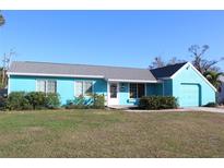 Light teal single story home with gray roof, white trim, and attached garage at 1322 Kenmore St, Port Charlotte, FL 33952