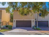 Tan colored townhouses with dark brown garages, and a shared paved driveway at 487 Pinellas Bayway S # 205, St Petersburg, FL 33715