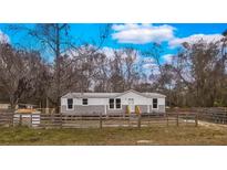 Newly built manufactured home with gray siding, wooden steps, and fenced yard at 13017 Manatee Ave, New Port Richey, FL 34654