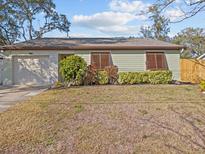 Charming single-story home with light green siding, brown shutters, and an attached one-car garage at 1310 Meres Blvd, Tarpon Springs, FL 34689