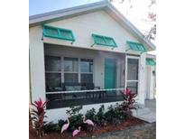 Charming home featuring a screened-in porch, turquoise door, and colorful landscaping at 301 E Grace St, Punta Gorda, FL 33950