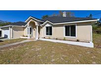 Tan house with a gray roof, white columns, and landscaping at 3522 E 26Th Ave, Tampa, FL 33605