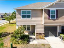 Tan two-story house with a gray door and small front yard at 10428 Rivercrest Dr, Riverview, FL 33578