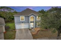Two-story house with gray exterior, white garage door, and landscaping at 1703 Alhambra Crest Dr, Ruskin, FL 33570