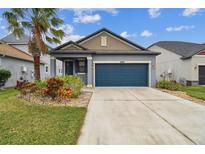 Two-story house with a blue garage door and landscaping at 21093 Wistful Yearn Dr, Land O Lakes, FL 34637